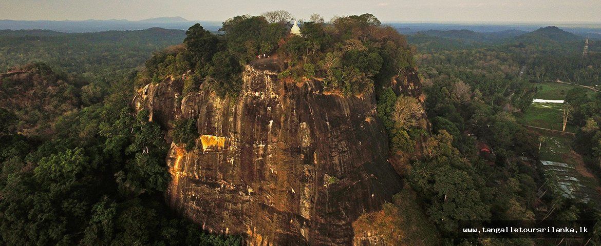 A large, rugged cliff with a small structure on top.
