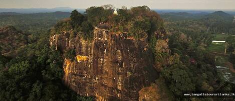 A large, rugged cliff with a small structure on top.