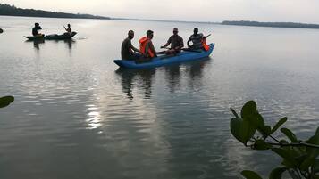 Un grupo de personas en un bote azul sobre un lago tranquilo, con árboles lejanos y un cielo despejado.