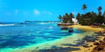 Una playa con agua turquesa cristalina, orilla de arena y palmeras.