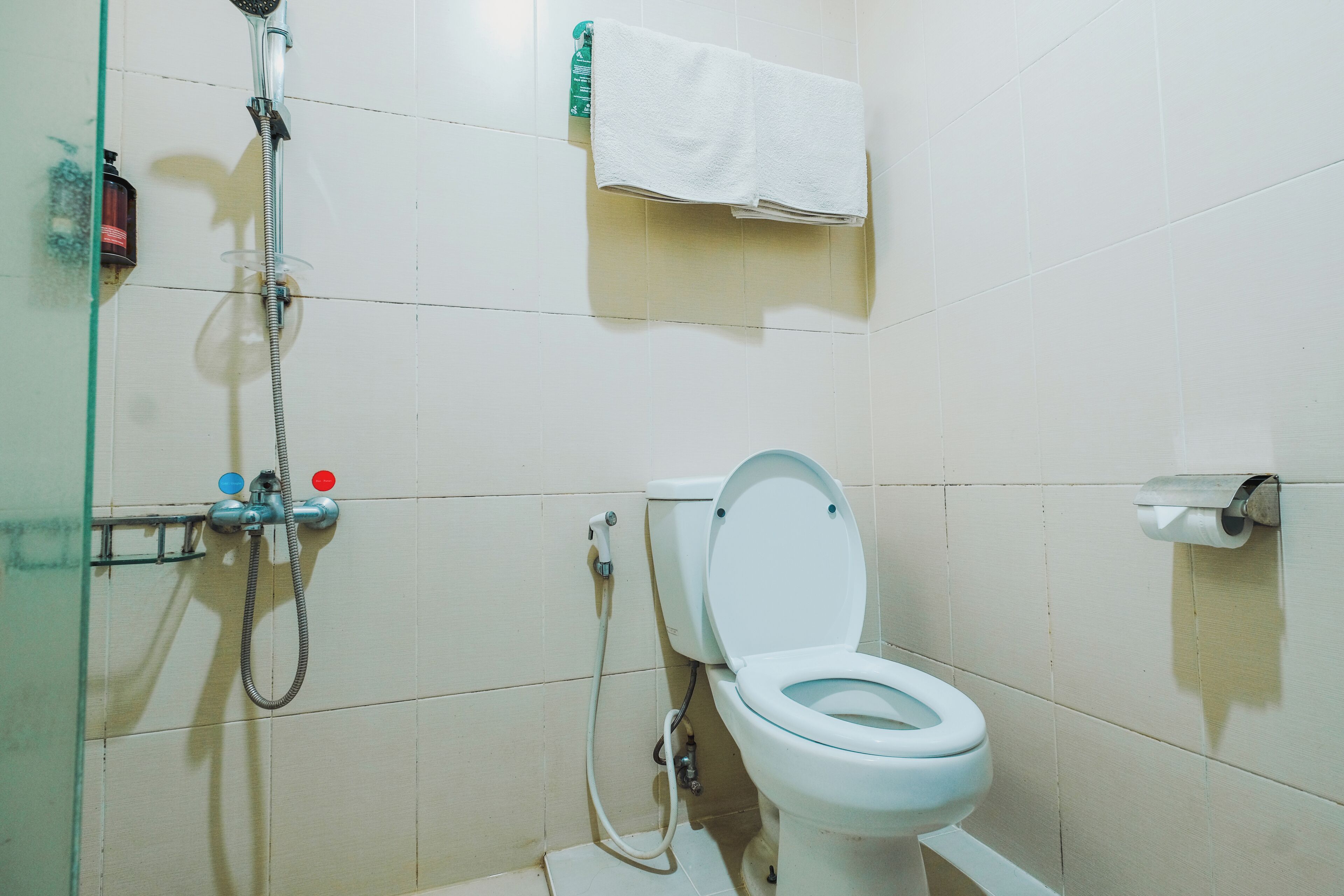Une salle de bain équipée de toilettes, d’une douche et d’un porte-serviettes.
