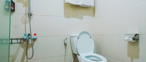 Une salle de bain équipée de toilettes, d’une douche et d’un porte-serviettes.