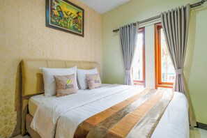 Habitación de hotel con cama, almohadas, un cuadro en la pared y cortinas.