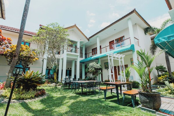 A courtyard with outdoor seating, a covered area, and a two-story building with balconies.