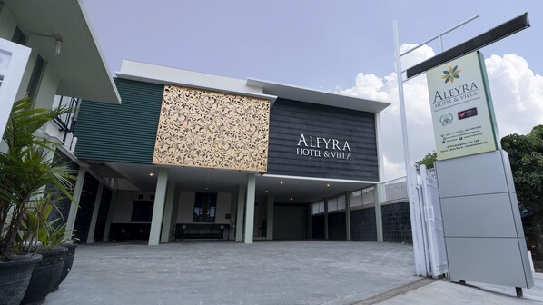 A modern hotel with a prominent sign for Aleyra Hotel & Villa.