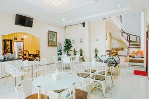 Un vestíbulo de hotel con zona de comedor, una escalera y un mostrador de recepción.