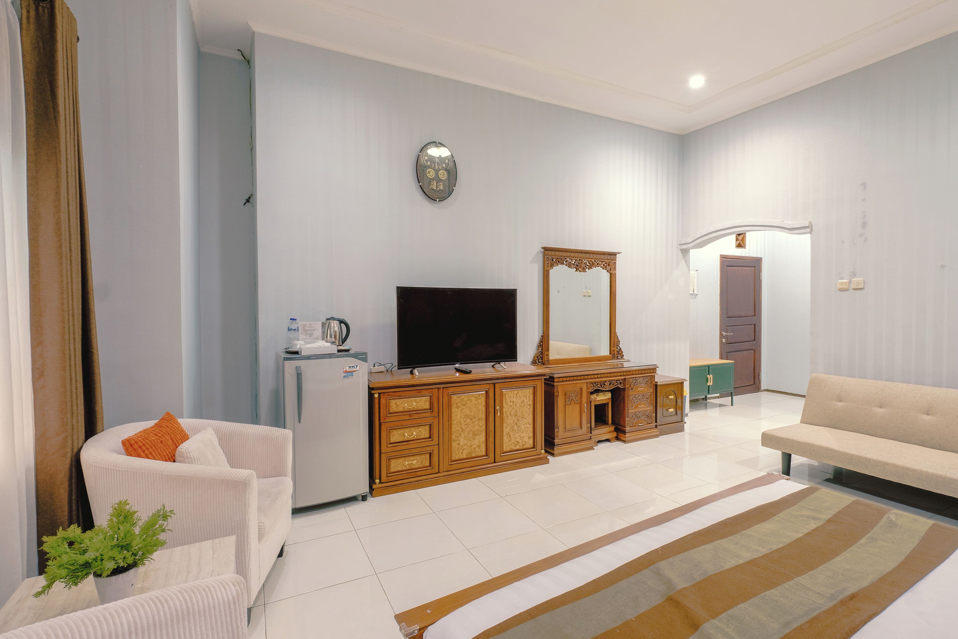 Una sala de estar con un sofá, un televisor, un mueble de madera y un espejo.