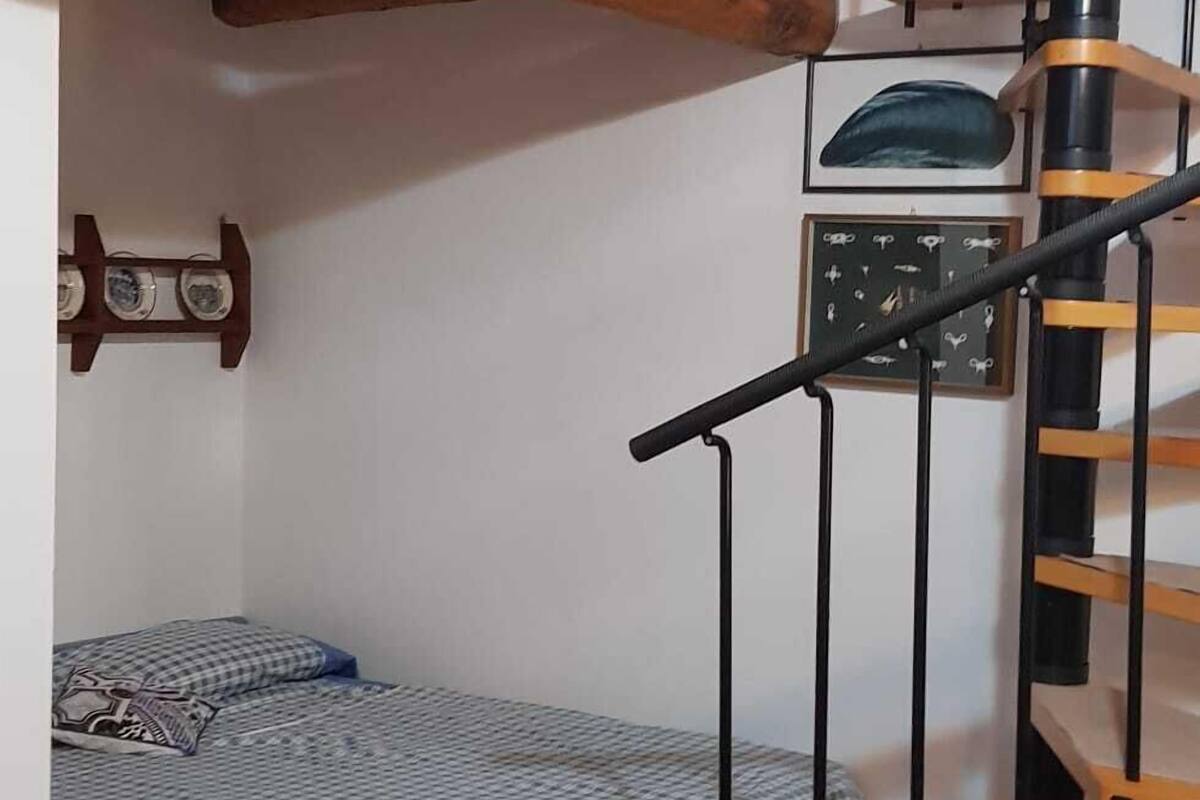 Une petite pièce comprenant un lit superposé, une petite table et un escalier en colimaçon.
