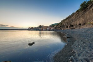 Eine Küstenstadt mit Häusern entlang der Uferlinie, einem ruhigen Meer und felsigen Klippen.