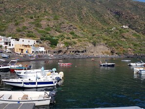 Une zone côtière où des bateaux sont amarrés, avec une côte rocheuse et des bâtiments en arrière-plan.
