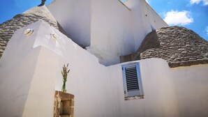 Ein Gebäude mit weißen Wänden und einem Steinziegeldach, einem kleinen Fenster und einem Zierteil am Dach.