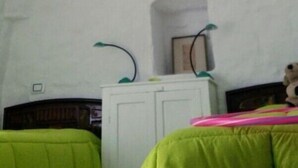 Ein Zimmer mit hohen Decken, einem weißen Kleiderschrank und einem Bett mit grüner Bettwäsche.