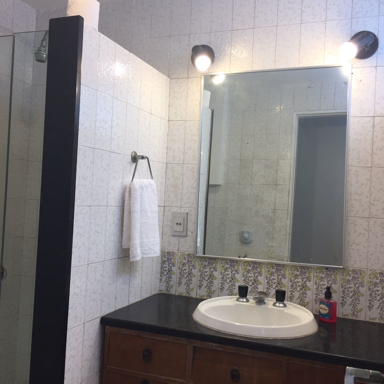 A bathroom with a white sink, a large mirror, and a towel hanging on a rack.