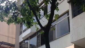 Un edificio moderno con balcón, ventanas amplias y un árbol en frente.