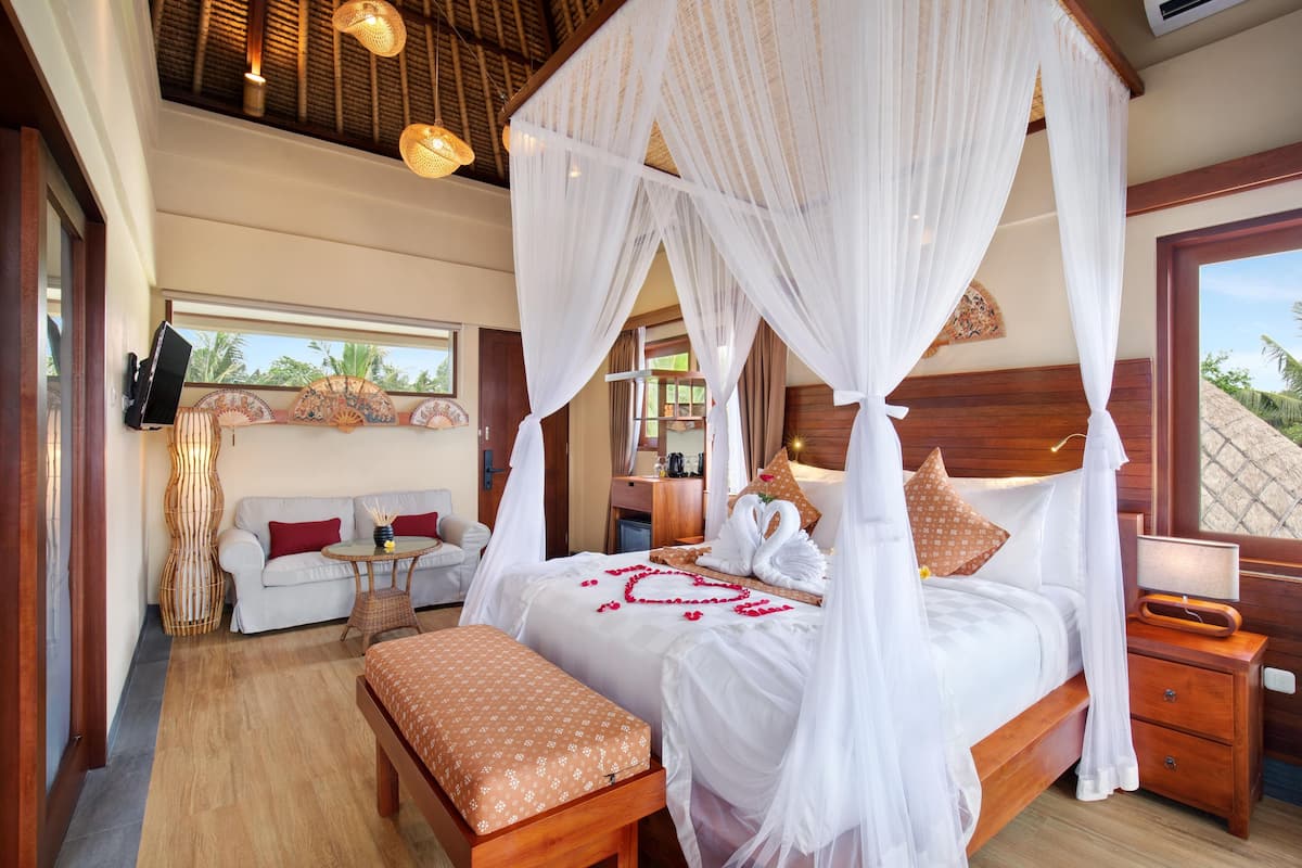 Een ruime slaapkamer met een groot bed, een zithoek en uitzicht op de omgeving.