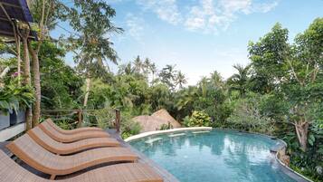 A pool with lounge chairs, surrounded by tropical vegetation.