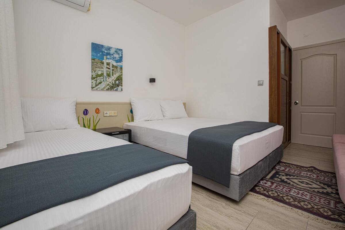 Ein Hotelzimmer mit zwei Betten, einem Nachttisch, einem Gemälde und einer Tür.
