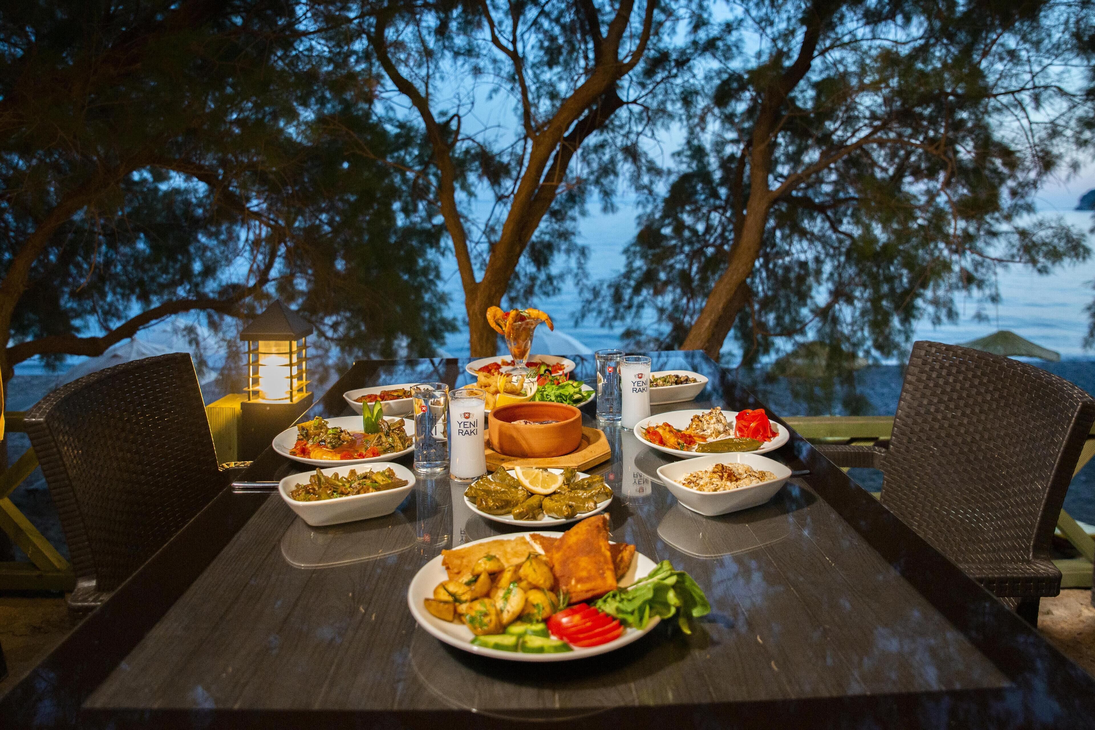 A dining table set outdoors with various dishes, a lantern, and chairs.
