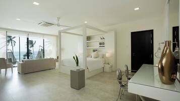 A modern hotel room with a large bed, a sitting area, a dining table, and a view of palm trees.