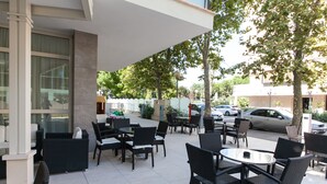 Eine Außenpatio mit schwarzer Rattanmöbel, Fliesenboden und Blick auf die Straße und geparkte Autos.