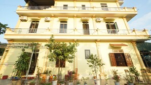 A two-story building with balconies, multiple windows, and potted plants in front. - Tam Coc Craft Homestay (Nam Hoa Lu)