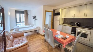 A compact living space with a kitchenette, a dining area, and a bed.