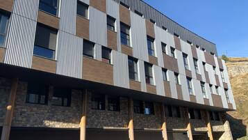 Un edificio moderno con fachada de ladrillo y metal, múltiples ventanas y techo plano.