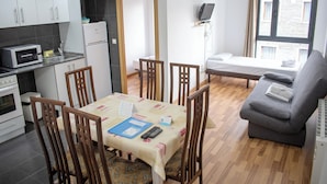 A compact living space with a dining area, kitchenette, and a sofa.