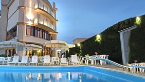 Un hôtel moderne doté d’une piscine, de chaises longues et de parasols.