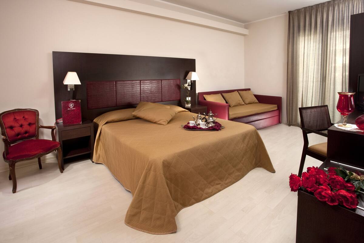 Een hotelkamer met een groot bed, een bank, een bureau met lamp en een televisie.