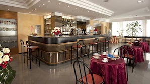 Un restaurant doté d’un bar, de plusieurs tables avec des chaises et d’une cuisine située à l’arrière.
