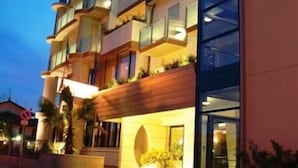 Un hôtel à plusieurs étages doté de balcons, de grandes fenêtres et d’une entrée bien éclairée.