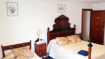 A bedroom with a wooden bed, a bedside table with a lamp, and two framed pictures on the wall.
