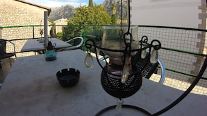 Una terraza con mesas al aire libre, un farol colgante y vistas a las montañas.