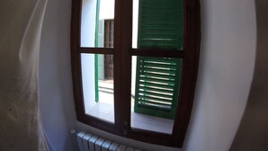 Una ventana con cuatro marcos, cada uno con contraventanas verdes, y un radiador blanco debajo.