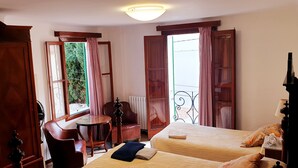 Habitación de hotel con dos camas, un armario de madera, una mesita y una silla.