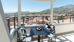 Un balcon avec une table et des chaises, d’où l’on a vue sur la ville et les montagnes.