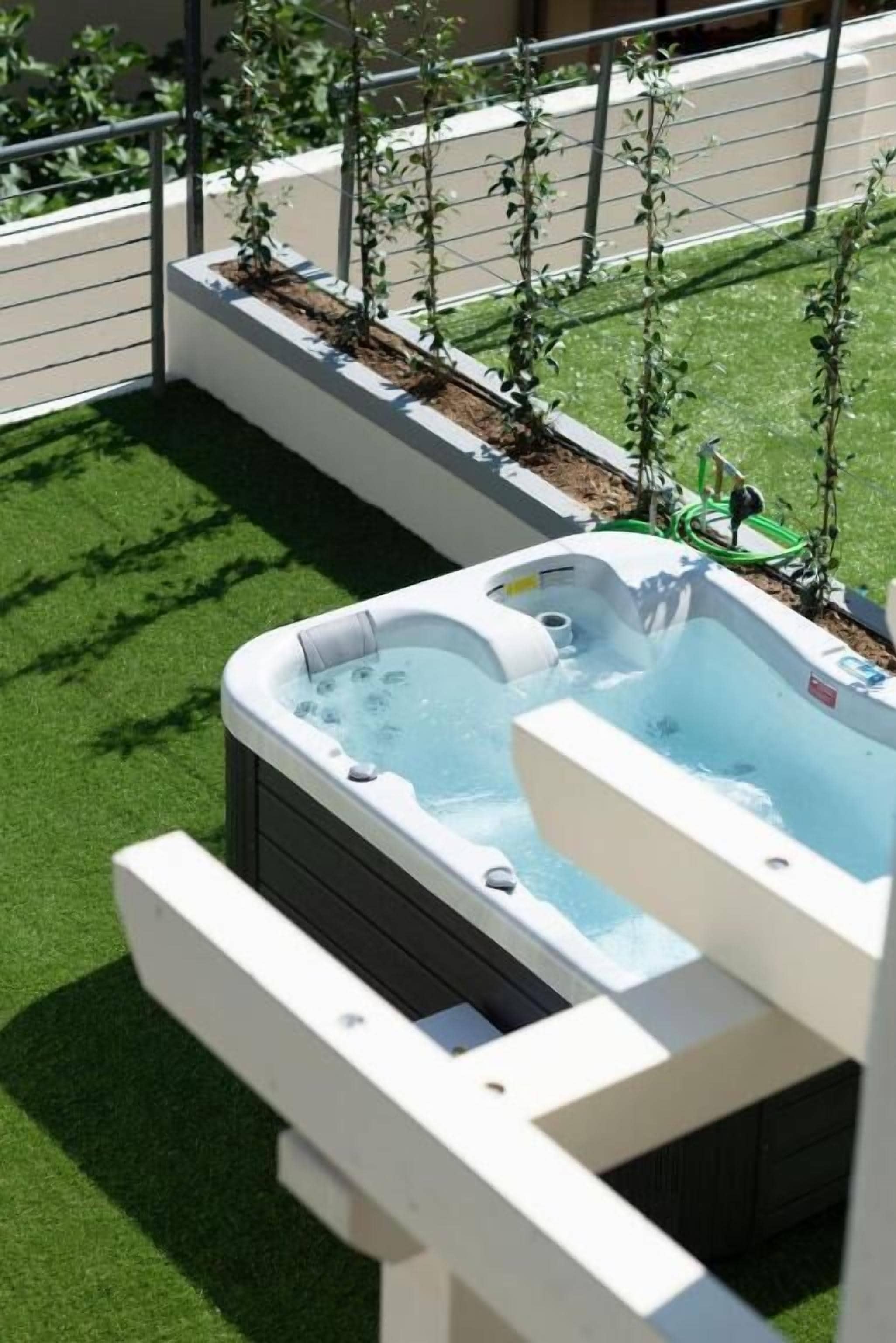 Un jacuzzi en la azotea con vistas a una calle de la ciudad y una fila de plantas.