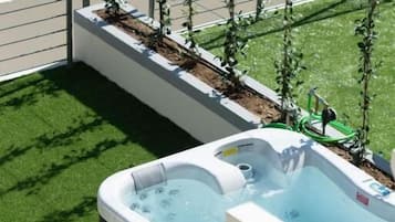 Un jacuzzi en la azotea con vistas a una calle de la ciudad y una fila de plantas.