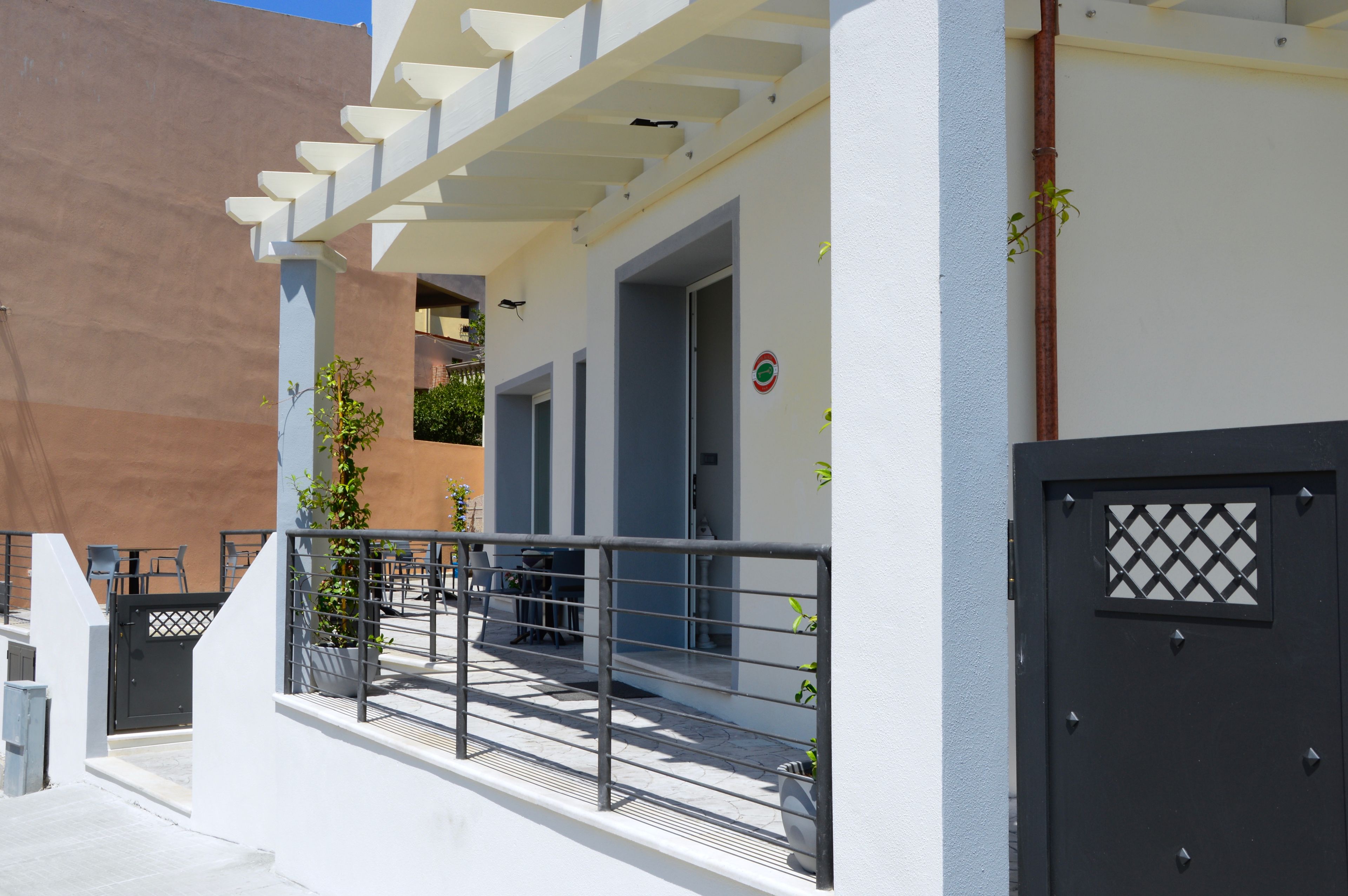 A modern building with a balcony, a gated entrance, and potted plants.