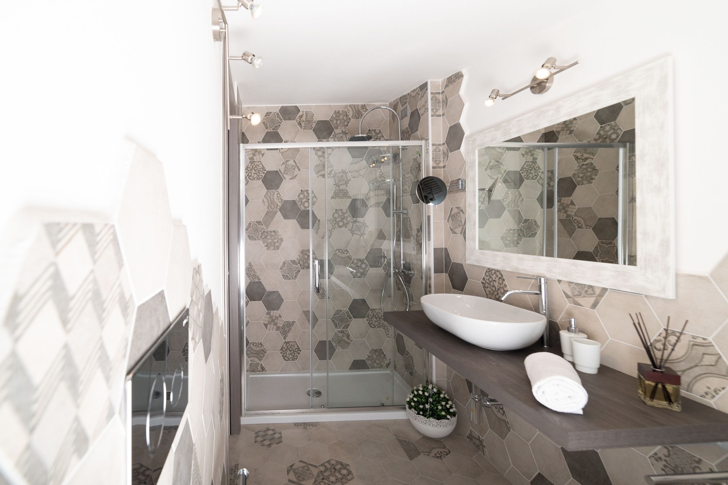 Een moderne badkamer met een douche met glazen wand, een grote spiegel en een wastafel.