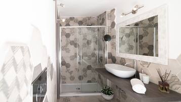 Een moderne badkamer met een douche met glazen wand, een grote spiegel en een wastafel.