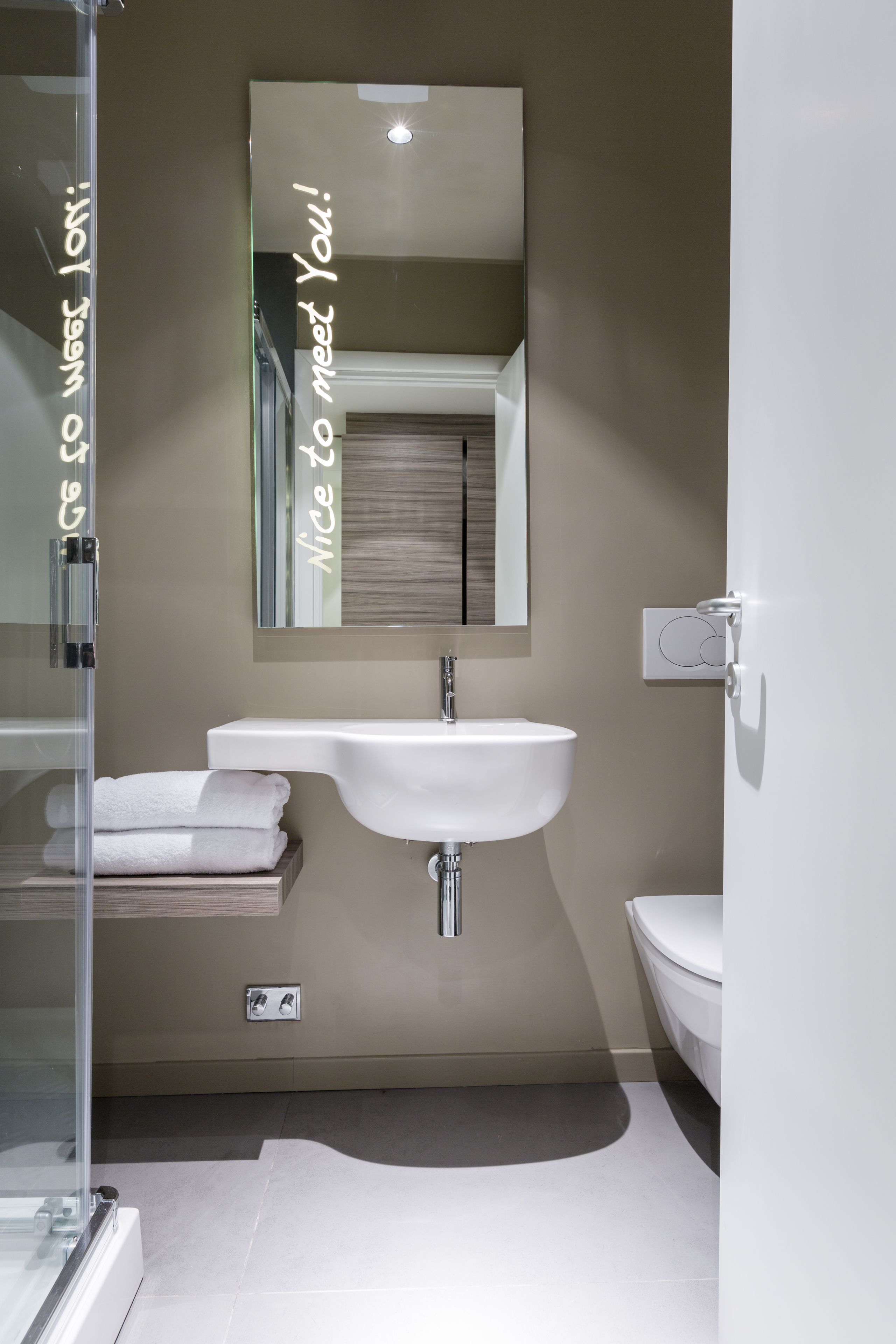 A modern bathroom with a glass shower enclosure, a white sink, and a toilet.