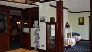 A hotel lobby with a marble floor, a reception desk, a glass display case, and a fireplace. - City Hotel Kassel (Kassel)