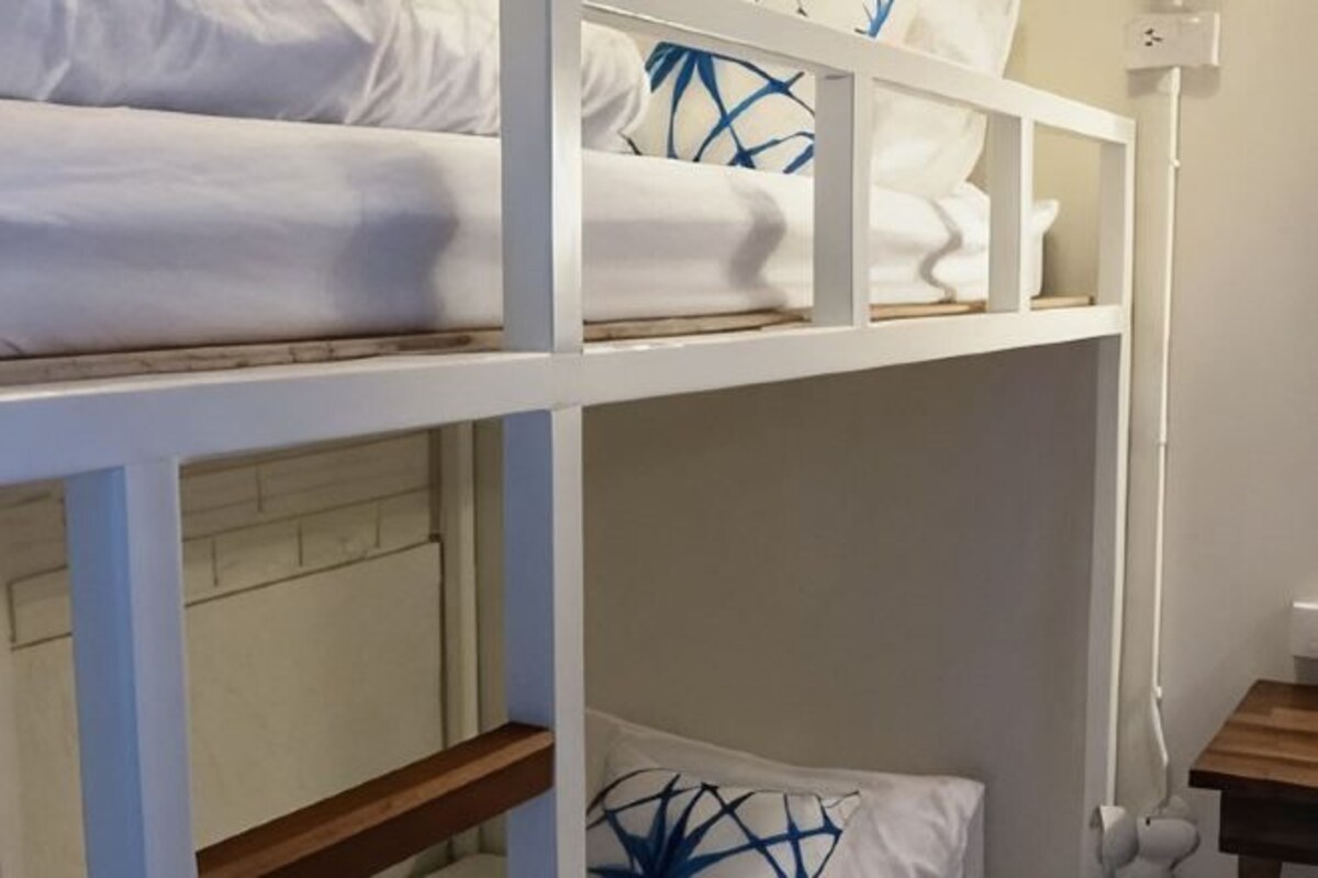 A bunk bed with white bedding and a pillow with a blue pattern.