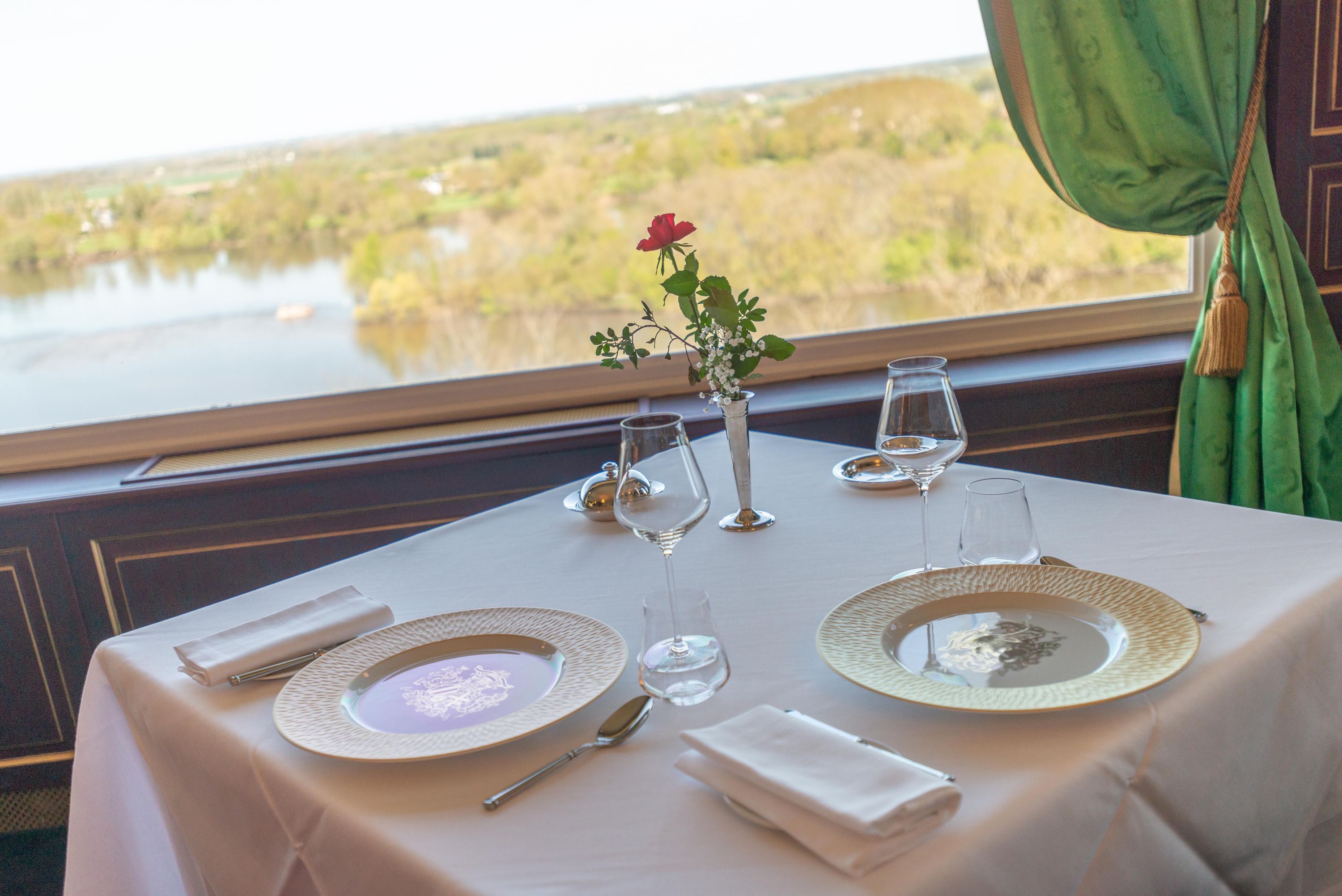 A table set for dining with a view of a lake and greenery.