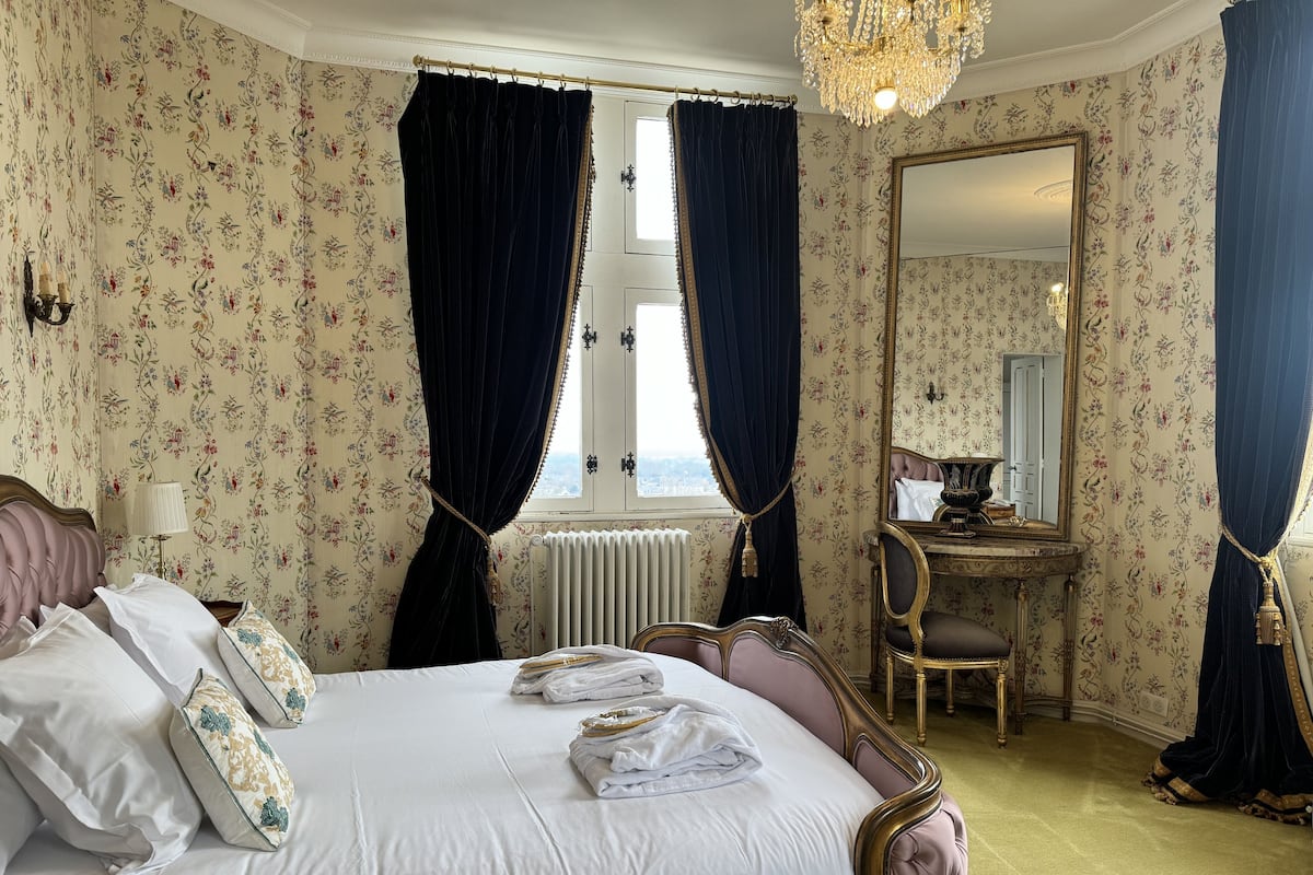 Een slaapkamer met een bed, een kaptafel, een spiegel en gordijnen.