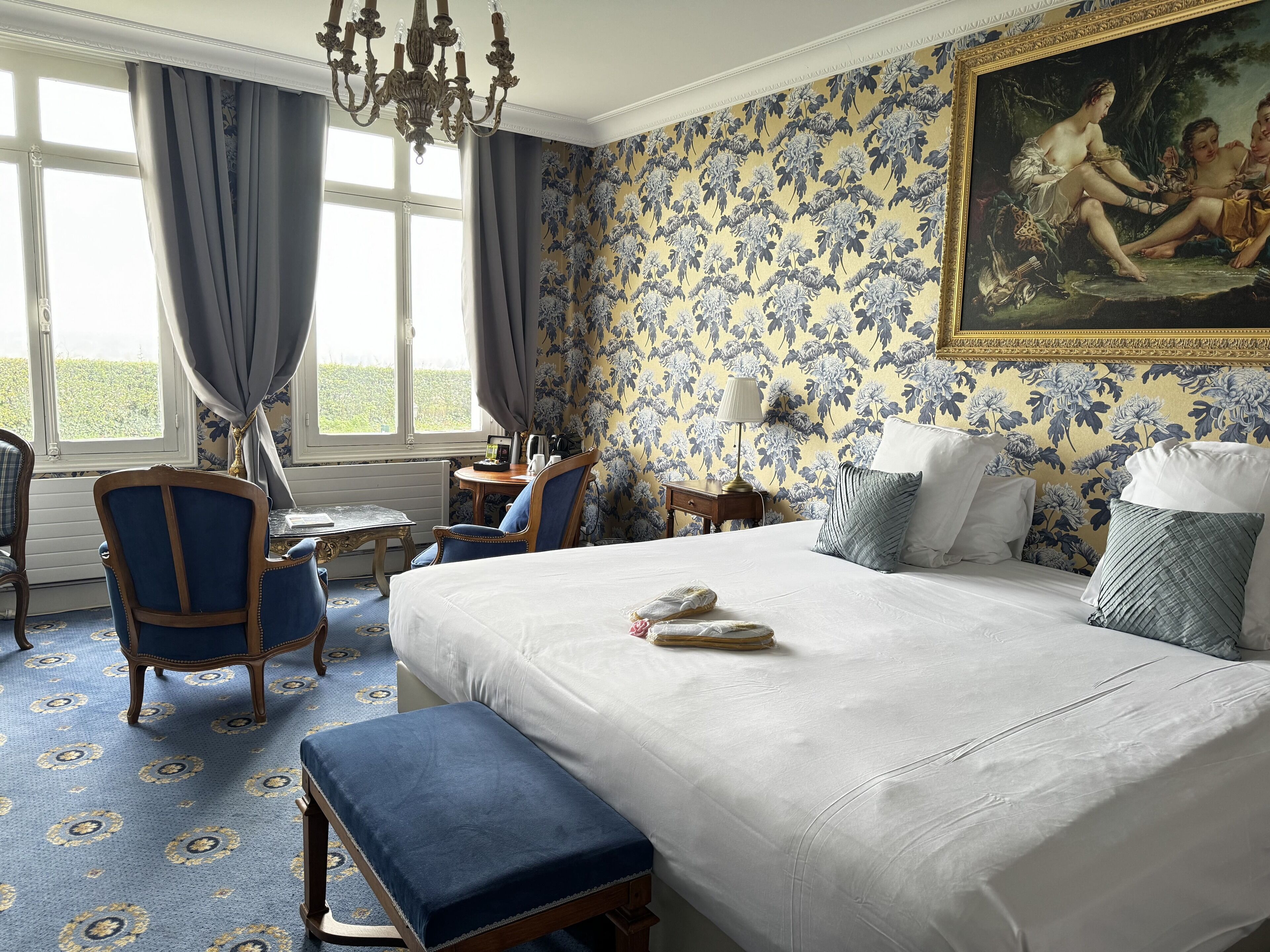 A bedroom with a large bed, a desk, a chair, and a painting on the wall.