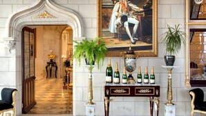 A grand lobby with a marble floor, a large portrait, and a display of champagne bottles.