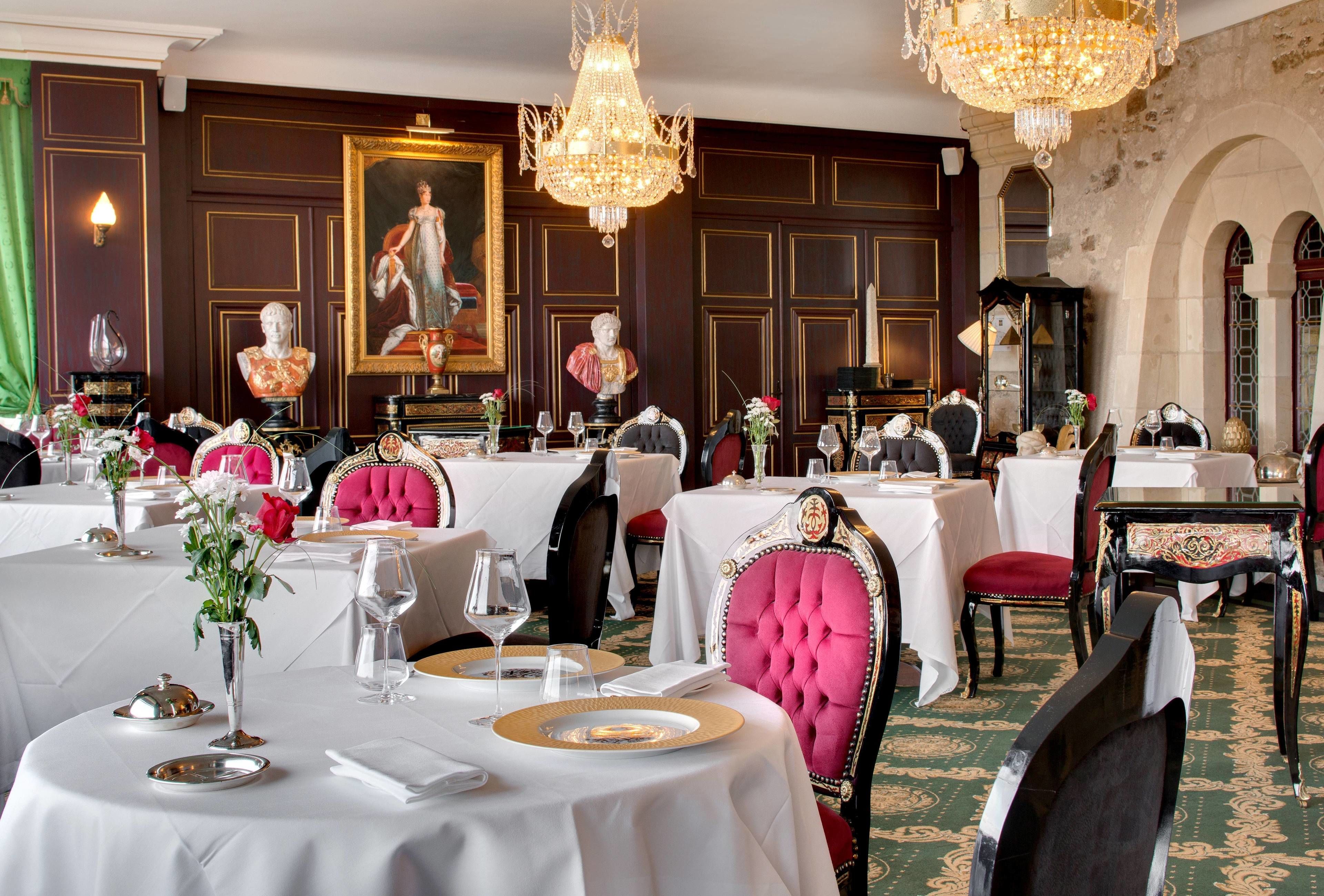 Un comedor formal con mesas redondas, sillas elegantes y candelabros.
